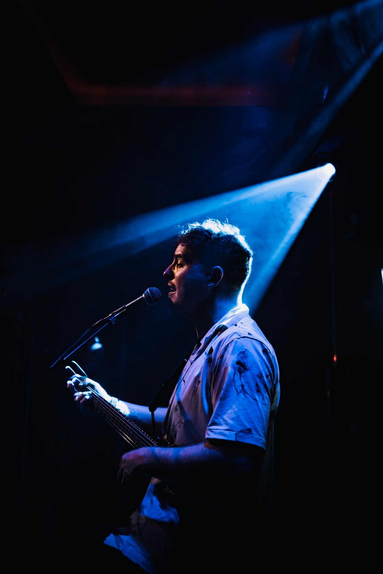 Kevin Neary singing under a blue stage spotlight